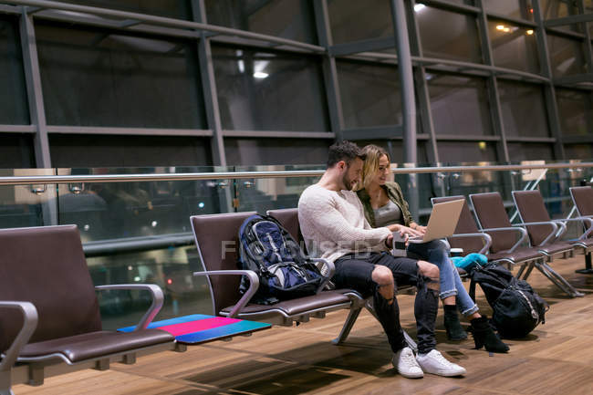 Пара використовує ноутбук у зоні очікування в аеропорту — стокове фото