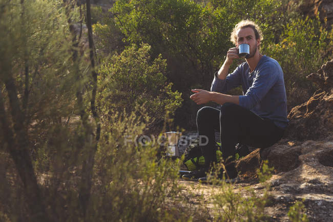 Мужчина-турист пьет кофе в сельской местности в солнечный день — стоковое фото
