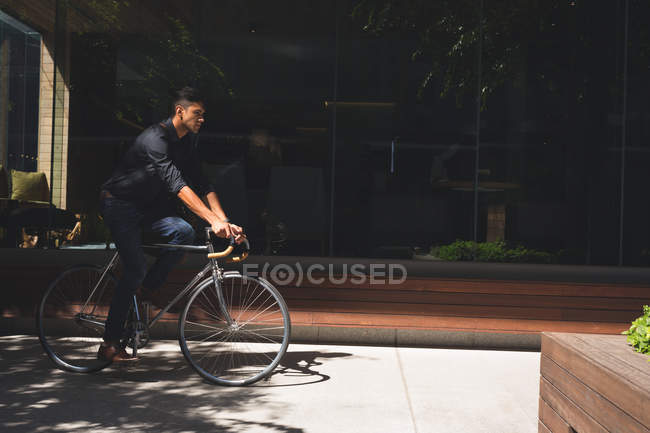 Молодий бізнесмен їде на велосипеді в офісних приміщеннях — стокове фото