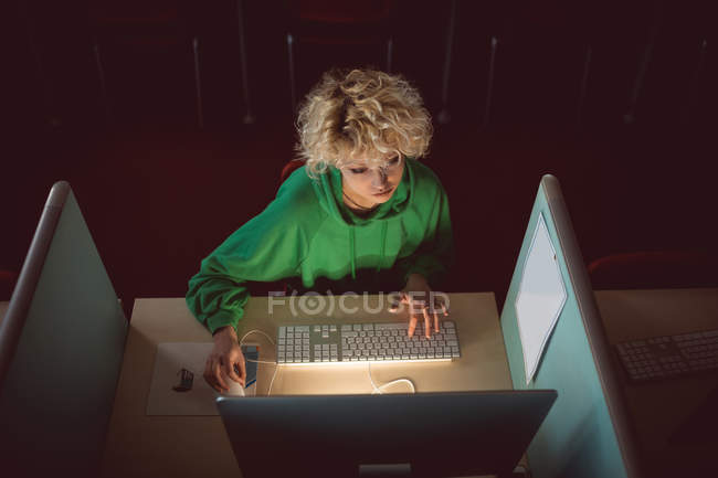 Mujer joven trabajando en la computadora en la biblioteca - foto de stock