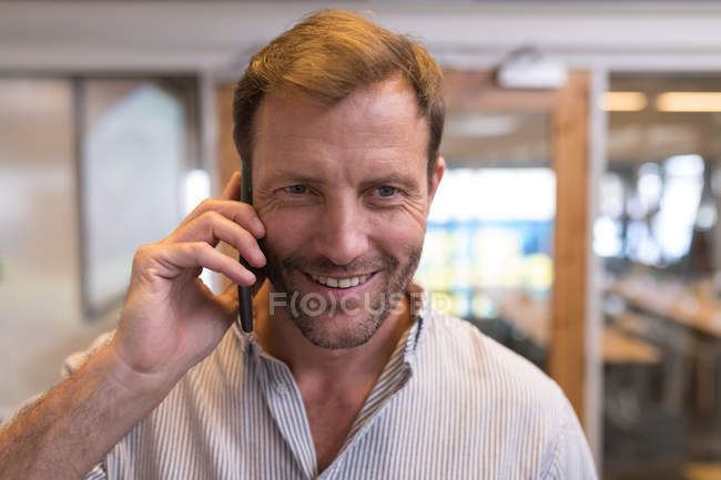 Male executive talking on mobile phone in office — Stock Photo