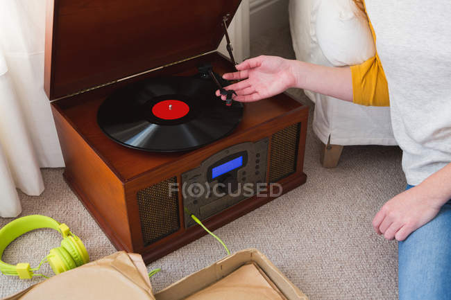Sección media de la mujer tocando un gramófono en casa - foto de stock