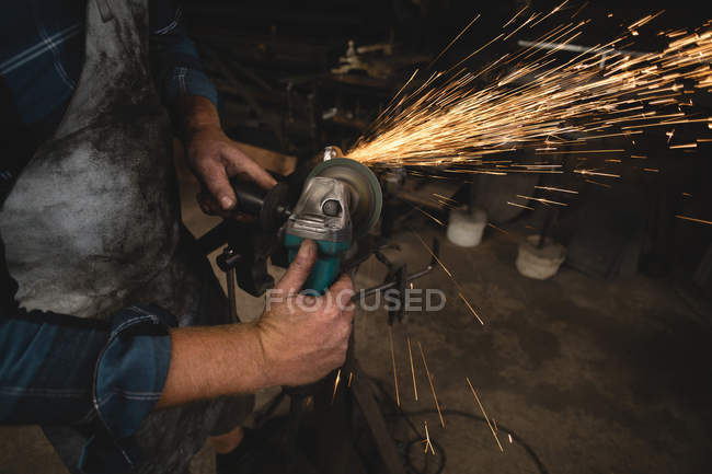 Schmied schleift Metallstange mit Schleifmaschine n Werkstatt — Stockfoto