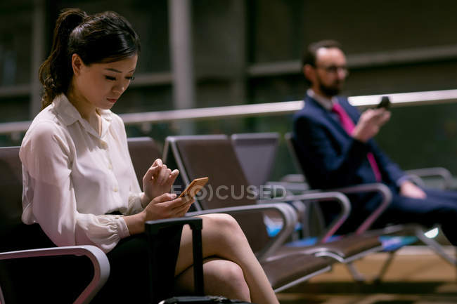 Mulher usando telefone celular na área de espera no aeroporto — Fotografia de Stock