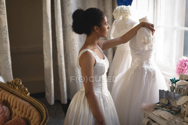 Mulher de raça mista, noiva de vestido branco olhando através da janela na boutique — Fotografia de Stock