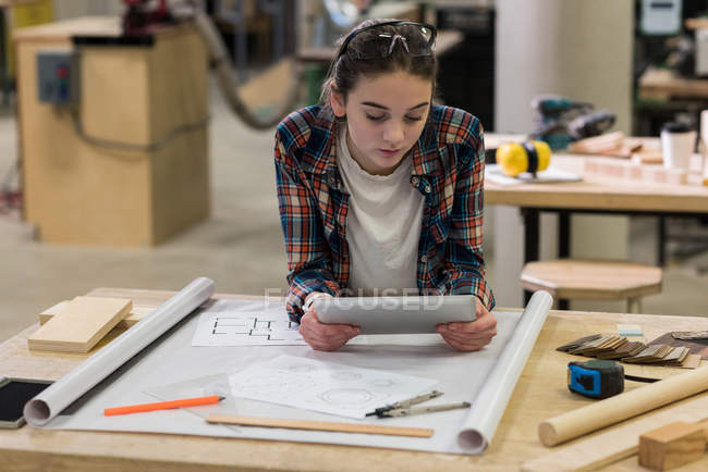 Carpinteiro feminino usando tablet digital na oficina — Fotografia de Stock