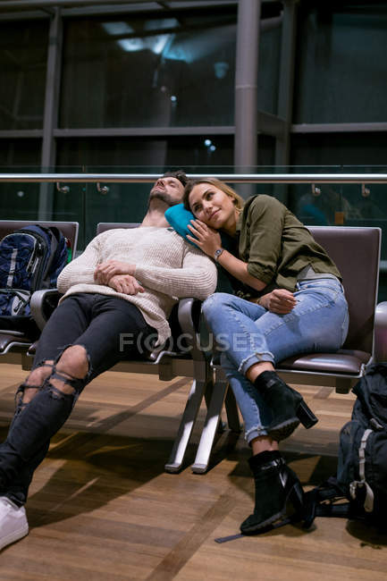 Pareja durmiendo en la sala de espera en el aeropuerto - foto de stock
