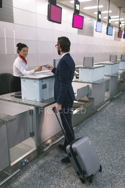 Flugbegleiter reicht Pendler am Schalter im Flughafenterminal den Reisepass — Stockfoto