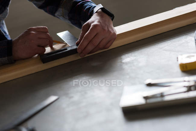 Carpinteiro macho fazendo medições de madeira na oficina — Fotografia de Stock