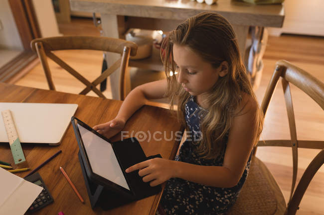 Внимательная девушка с цифровым планшетом дома, сидя за столом — стоковое фото