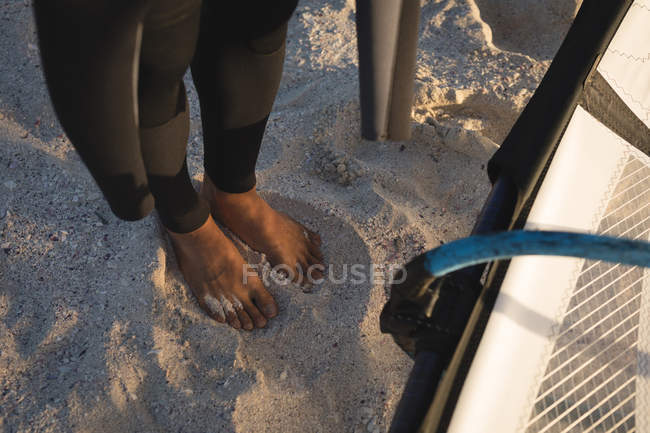 Bassa sezione di surfista maschio in piedi con aquilone sulla spiaggia — Foto stock