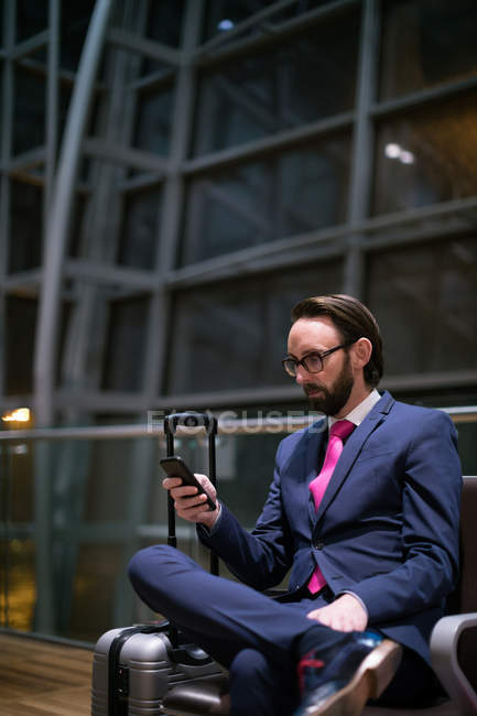 Homme d'affaires utilisant le téléphone portable dans la salle d'attente au terminal de l'aéroport — Photo de stock