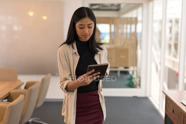 Молодая женщина-руководитель с помощью цифрового планшета в офисе — стоковое фото