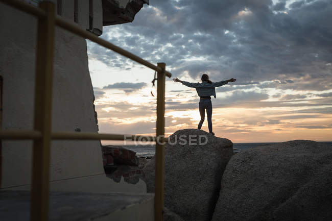 Вид ззаду жінки, що стоїть з руками, витягнутими на пляжі — стокове фото