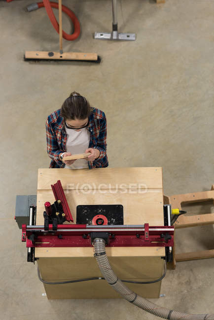 Female carpenter examining a piece of wood furniture at workshop — Stock Photo