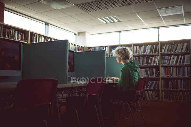 Молода жінка працює на комп'ютері в бібліотеці — стокове фото