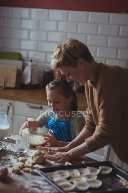 Madre e hija preparando magdalena en la cocina en casa - foto de stock