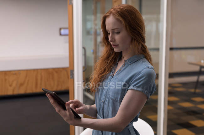 Jovem executiva usando tablet digital no escritório — Fotografia de Stock