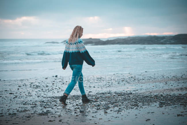 Mujer pensativa caminando en una playa - foto de stock
