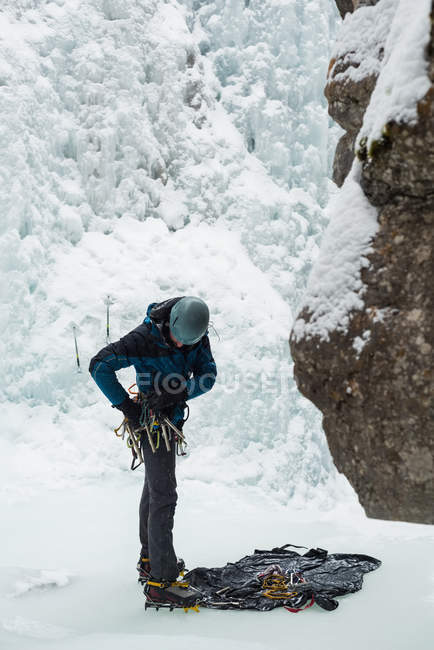 Male rock climber wearing harness near rocky mountain during winter — Stock Photo