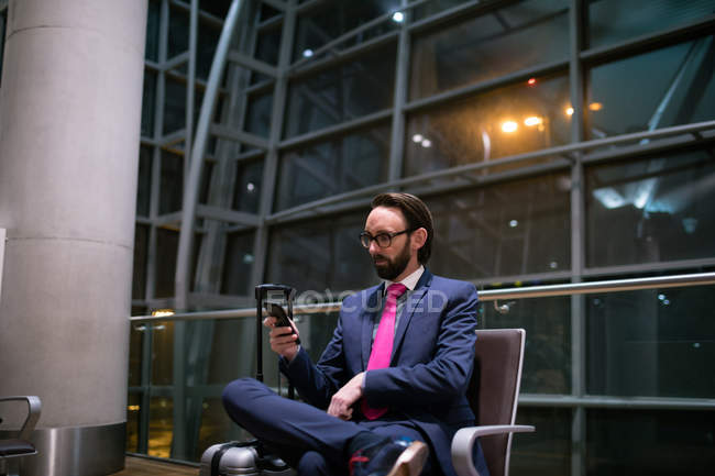 Empresário usando telefone celular na área de espera no terminal do aeroporto — Fotografia de Stock