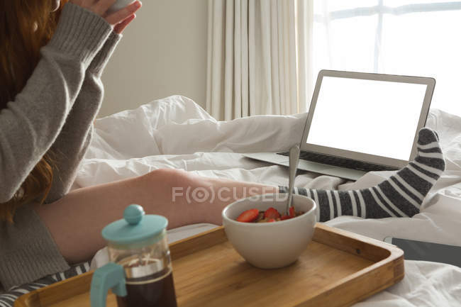 Mujer con desayuno relajante en el dormitorio en casa - foto de stock