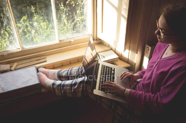 Frau benutzte Laptop in der Nähe von Fenster zu Hause — Stockfoto