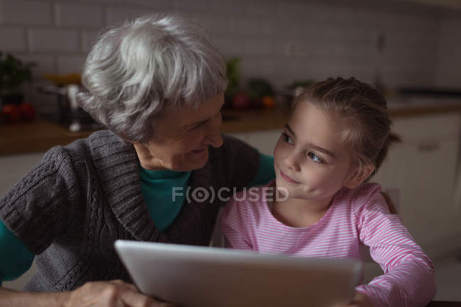 Großmutter und Enkelin nutzen digitales Tablet in der heimischen Küche — Stockfoto