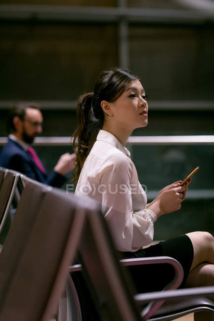 Mujer usando teléfono móvil en la sala de espera en el aeropuerto - foto de stock