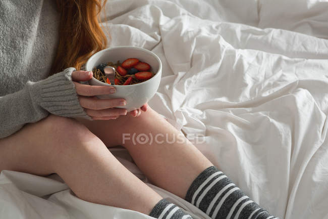 Woman holding bowl of breakfast in bedroom at home — Stock Photo
