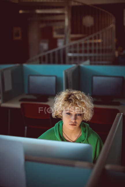 Молодая женщина, работающая за компьютером в библиотеке — стоковое фото