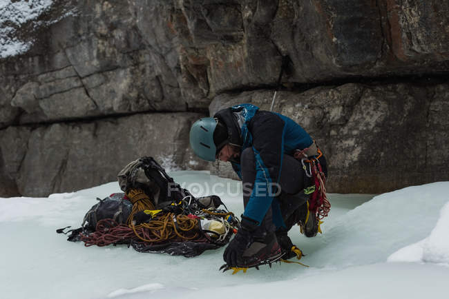Bergsteiger trägt im Winter Steigeisen in der Nähe von felsigen Bergen — Stockfoto