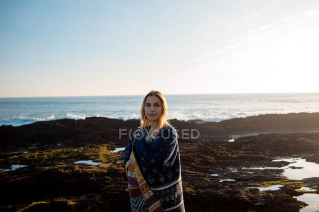 Portrait of woman in shawl standing on a beach — Stock Photo