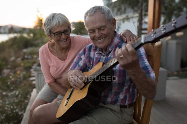 Happy senior couple playing guitar in the porch — Stock Photo