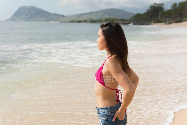 Frau steht an einem sonnigen Tag am Strand — Stockfoto