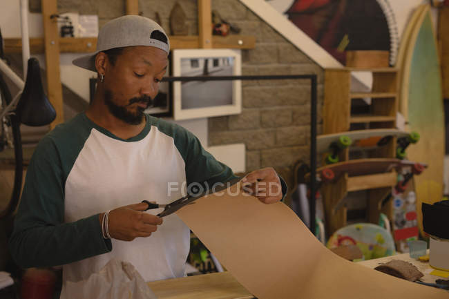 Mann schneidet Papppapier in Werkstatt — Stockfoto