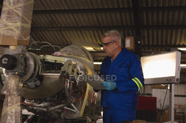 Инженер, изучающий авиационную часть в аэрокосмическом ангаре — стоковое фото