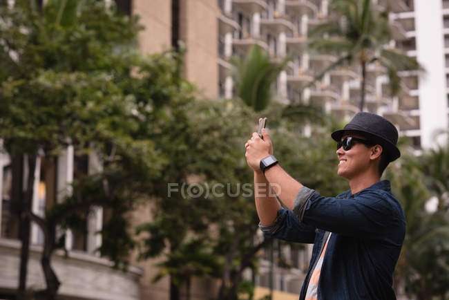 Uomo cliccando foto con cellulare in città — Foto stock
