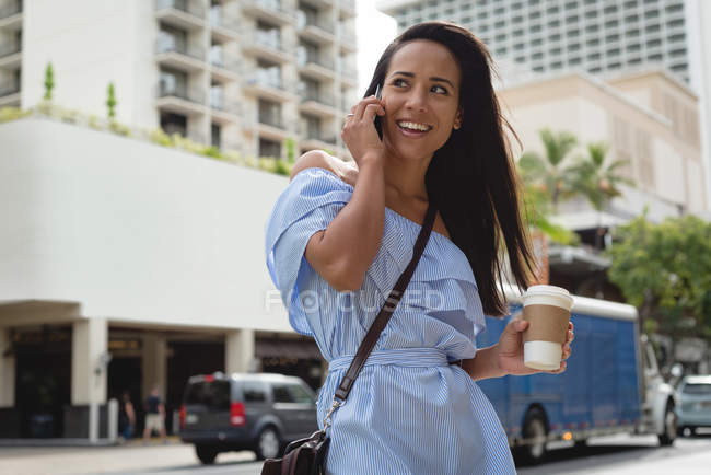 Усміхнена жінка розмовляє по мобільному телефону на міській вулиці — стокове фото