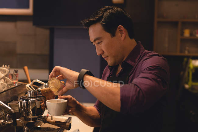 Serveur masculin préparant le café dans le café — Photo de stock