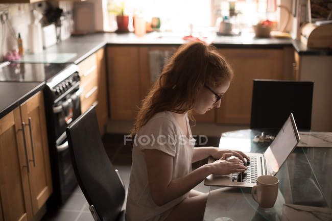 Красива жінка використовує ноутбук вдома — стокове фото