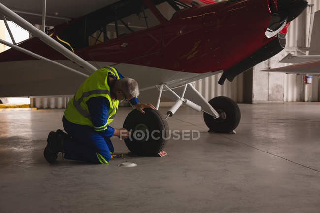 Ingenieur überprüft Reifen von Flugzeug in Flugzeughangar — Stockfoto