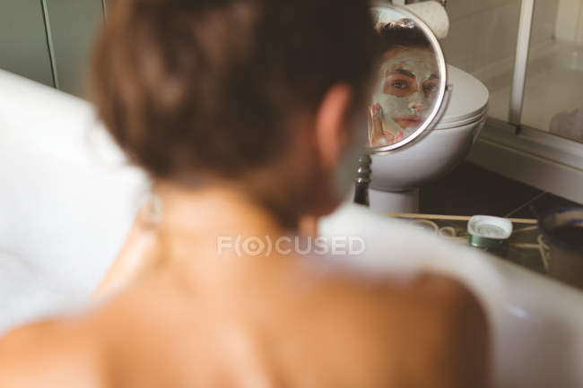 Mulher aplicando creme hidratante enquanto toma banho no banheiro em casa — Fotografia de Stock
