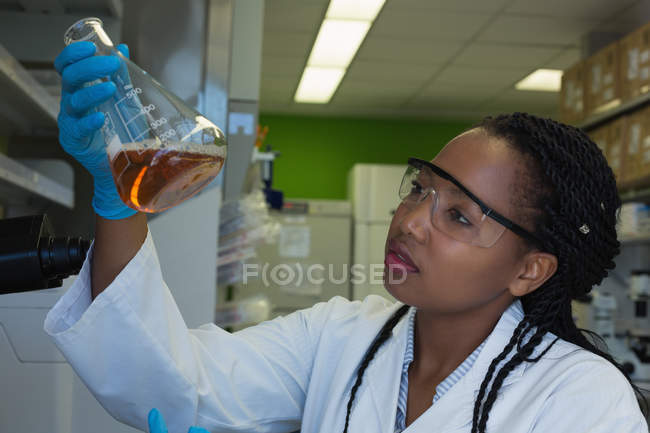 Wissenschaftler prüft Lösung in konischem Kolben im Labor — Stockfoto