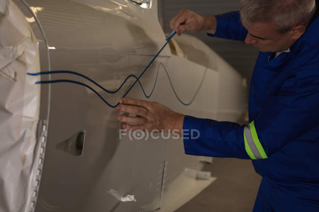 Mecánico marcando una línea en las partes del avión en el hangar aeroespacial - foto de stock