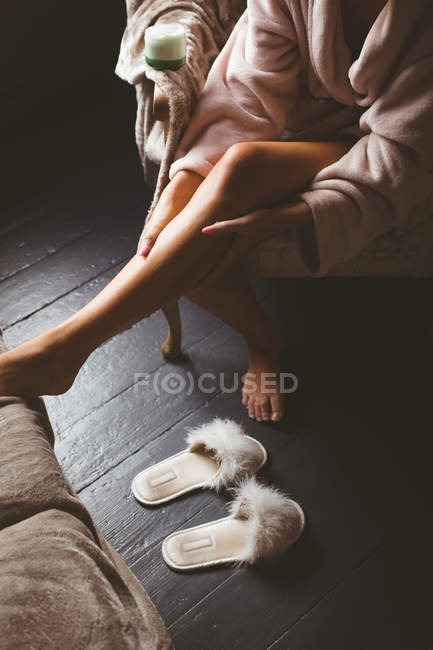 Section basse de la femme qui applique une lotion corporelle à la maison — Photo de stock