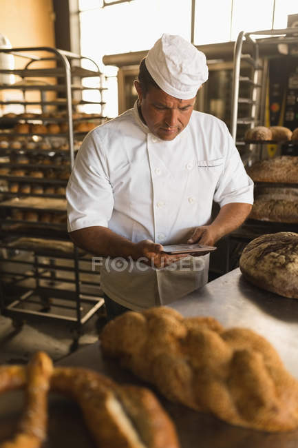 Male baker using digital tablet in bakery shop — Stock Photo