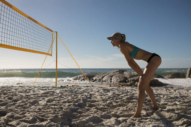 Joueuse de volley-ball jouant au football sur la plage — Photo de stock
