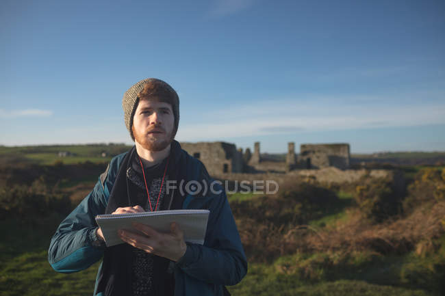 Young male hiker standing with notepad at countryside — Stock Photo