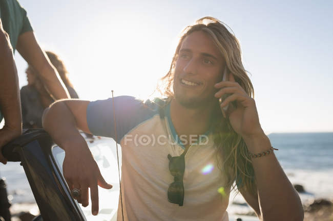 Mann telefoniert an einem sonnigen Tag am Strand — Stockfoto